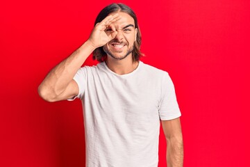 Fototapeta premium Young handsome man wearing casual clothes doing ok gesture with hand smiling, eye looking through fingers with happy face.