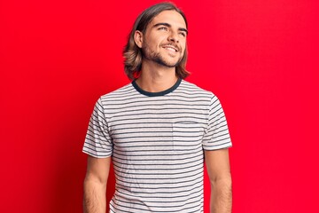 Fototapeta premium Young handsome man wearing casual clothes looking away to side with smile on face, natural expression. laughing confident.