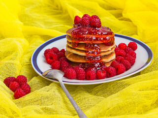 pancakes with ripe raspberries and raspberry jam on a plate spoon