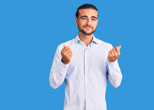 Young handsome man wearing business clothes doing money gesture with hands, asking for salary payment, millionaire business