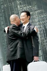 A bald man hugging a bespectacled man