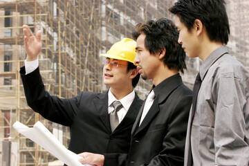 Two men and an architect at the construction site