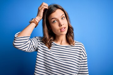 Young beautiful blonde girl wearing casual sweater standing over blue isolated background confuse...