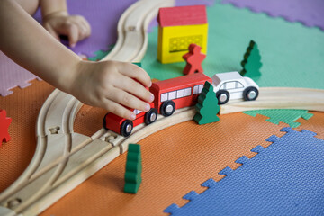 Child is playing with wooden railway track toy on the floor