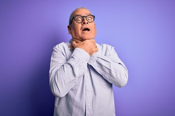 Middle age handsome hoary man wearing striped shirt and glasses over purple background shouting and suffocate because painful strangle. Health problem. Asphyxiate and suicide concept.