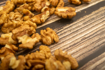 Peeled walnuts scattered on a wooden table. Healthy diet. Fitness diet. Close up.