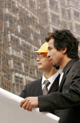 Architect discussing a building plan with his client at a construction site