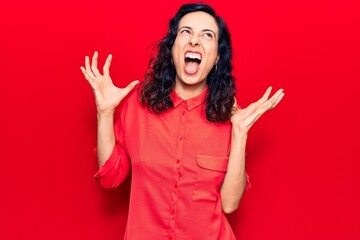 Young beautiful hispanic woman wearing casual clothes crazy and mad shouting and yelling with...
