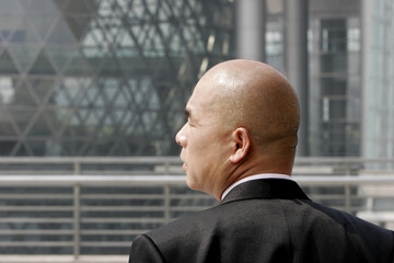 Back shot of a bald man in business suit looking to the side