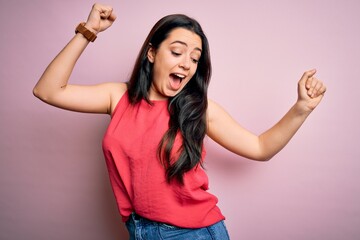 Young brunette woman wearing casual summer shirt over pink isolated background Dancing happy and cheerful, smiling moving casual and confident listening to music