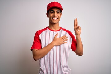 Young handsome african american sportsman wearing striped baseball t-shirt and cap smiling swearing...