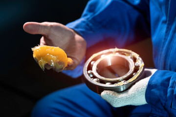 Mechanic is putting yellow grease in the into bearing, engineering and industrial concept. - obrazy, fototapety, plakaty
