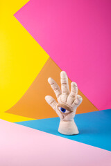 Protective amulet in the shape of an open palm and eye made of felted vul on a colored background