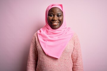 Young african american plus size woman wearing muslim hijab over isolated pink background with a happy and cool smile on face. Lucky person.