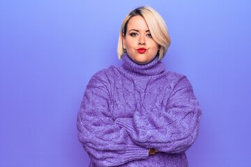 Beautiful blonde plus size woman wearing casual turtleneck sweater over purple background skeptic and nervous, disapproving expression on face with crossed arms. Negative person.