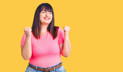 Young plus size woman wearing casual clothes excited for success with arms raised and eyes closed celebrating victory smiling. winner concept.