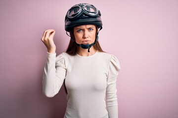 Young beautiful motorcyclist woman with blue eyes wearing moto helmet over pink background Doing Italian gesture with hand and fingers confident expression