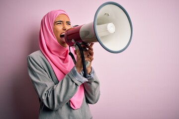 Business arab woman wearing hijab shouting angry on protest through megaphone. Yelling excited on...