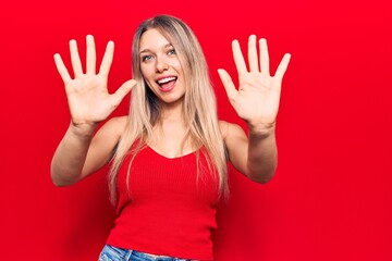 Young blonde woman wearing casual clothes showing and pointing up with fingers number ten while smiling confident and happy.