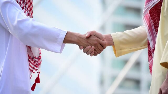 Arab Businessman shaking hands together. Teamwork business partner wear Muslim dress Shake Hands with Partnership Concept. Success UAE diversity people trust make commitment by handshake
