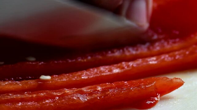 Extreme closeup of a red pepper being chopped.