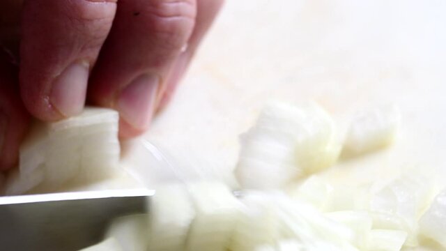 Extreme closeup of a knife mincing an onion