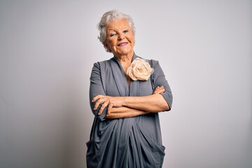 Senior beautiful grey-haired woman wearing casual dress standing over white background happy face smiling with crossed arms looking at the camera. Positive person.