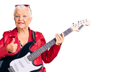 Senior beautiful woman with blue eyes and grey hair wearing a modern look playing electric guitar doing happy thumbs up gesture with hand. approving expression looking at the camera showing success.