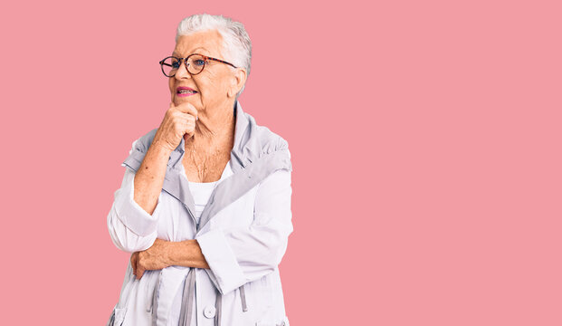 Senior beautiful woman with blue eyes and grey hair wearing casual clothes and glasses with hand on chin thinking about question, pensive expression. smiling with thoughtful face. doubt concept.