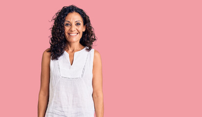 Middle age beautiful woman wearing casual sleeveless t shirt looking positive and happy standing...