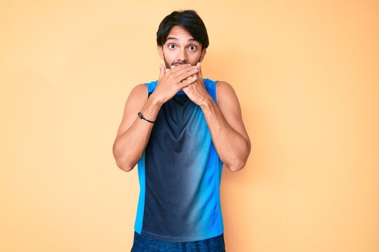 Handsome hispanic man wearing sportswear shocked covering mouth with hands for mistake. secret concept.