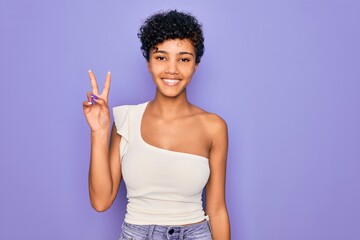 Young beautiful african american afro woman wearing casual t-shirt over purple background smiling looking to the camera showing fingers doing victory sign. Number two.