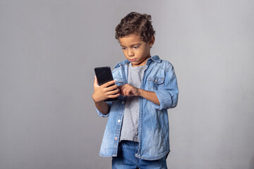 White curly haired boy using smartphone