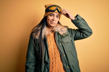Young beautiful hispanic woman wearing ski glasses and coat for winter weather worried and stressed about a problem with hand on forehead, nervous and anxious for crisis