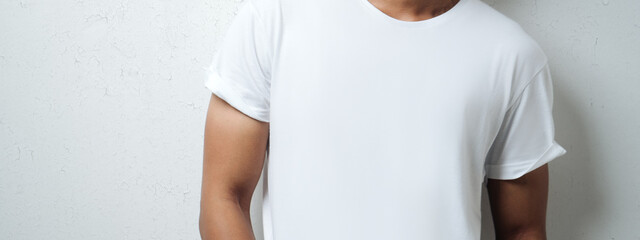 man in white blank t-shirt, grunge wall, studio close-up. Wide screen, panoramic