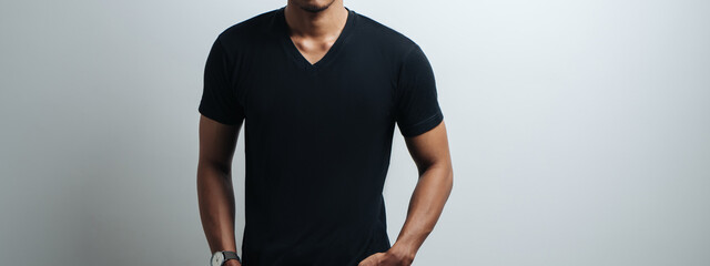 guy in black blank t-shirt, empty wall, studio portrait. Wide screen, panoramic