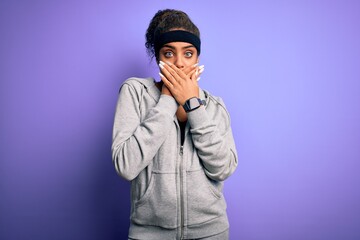 Obraz premium Young african american sportswoman doing sport wearing sportswear over purple background shocked covering mouth with hands for mistake. Secret concept.