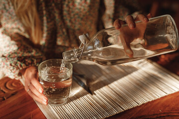 Hands closeup woman pour water from bottle on the glass, sit in cafe by the table