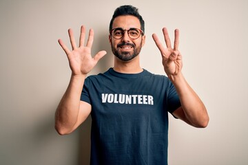 Handsome man with beard wearing t-shirt with volunteer message over white background showing and...