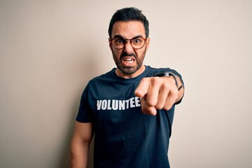 Handsome man with beard wearing t-shirt with volunteer message over white background pointing...