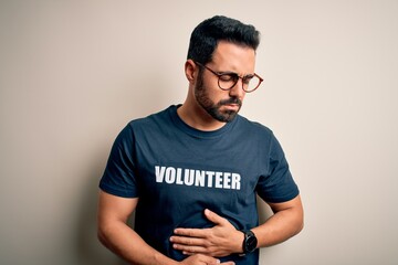 Handsome man with beard wearing t-shirt with volunteer message over white background with hand on...