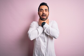 Fototapeta premium Young handsome man with beard wearing casual shirt standing over pink background shouting and suffocate because painful strangle. Health problem. Asphyxiate and suicide concept.