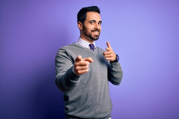 Handsome businessman with beard wearing casual tie standing over purple background pointing fingers to camera with happy and funny face. Good energy and vibes.