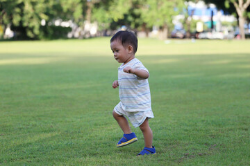 Asian boy is learning to walk in the garden.