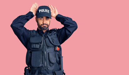 Young hispanic man wearing police uniform doing bunny ears gesture with hands palms looking cynical and skeptical. easter rabbit concept.
