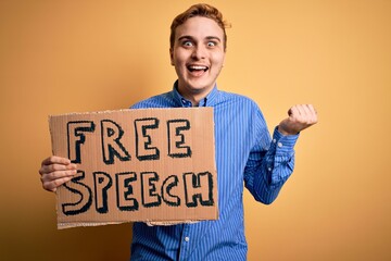 Young handsome redhead man asking for freedom holding banner with free speech message screaming proud, celebrating victory and success very excited with raised arms