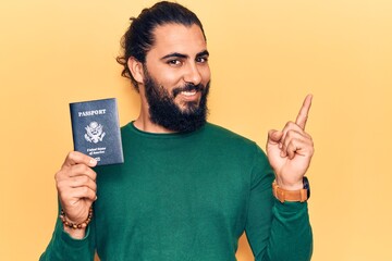 Young arab man holding united states passport smiling happy pointing with hand and finger to the side
