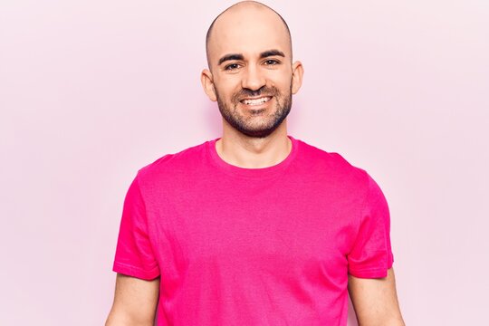 Young handsome bald man wearing casual t shirt with a happy and cool smile on face. lucky person.