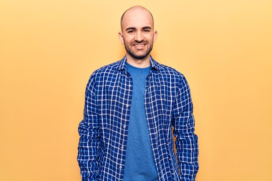 Young handsome bald man wearing casual shirt with a happy and cool smile on face. lucky person.