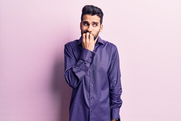Young handsome man with beard wearing casual shirt looking stressed and nervous with hands on mouth biting nails. anxiety problem.